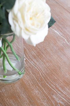 white flowers in a clear glass vase on a wooden table