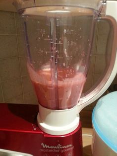 a blender filled with pink liquid on top of a counter