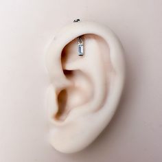 an ear is shown with a small piece of jewelry hanging from it