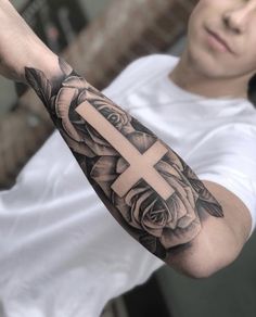 a man with a cross and roses tattoo on his arm