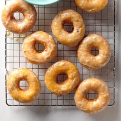 six glazed donuts sitting on a cooling rack next to a bowl of dipping sauce