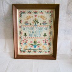 a cross - stitch sample in a wooden frame with the words true friend is a gift of god