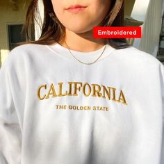 "*SIZES ARE UNISEX* -I'd suggest your usual size for a more fitted look, or sizing up for a more relaxed fit. *these sweatshirts are extra comfy when oversized \"California The Golden State embroidered on a comfy vintage-style crewneck. If you're on the lookout for both style and comfort, this retro sweatshirt is the perfect choice. * 50% cotton, 50% polyester * Pre-shrunk * Classic fit with no center crease * 1x1 athletic rib knit collar with spandex * Air-jet spun yarn with a soft feel and red Varsity T-shirt With Embroidered Graphics For Fall, Trendy Oversized Embroidered Sweatshirt, College Crew Neck Sweater With Embroidered Graphics, Crew Neck Sweatshirt With Letter Embroidery For College, College Crew Neck Sweater With Letter Embroidery, Oversized College Sweatshirt With Embroidered Graphics, Oversized Embroidered College Sweatshirt, Oversized Embroidered Sweatshirt For College, Oversized White Sweatshirt With Letter Embroidery