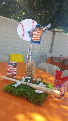 a baseball themed centerpiece on top of a table with grass and rocks in front of it