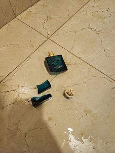 two bottles of cologne sitting on the floor next to each other in a tiled bathroom