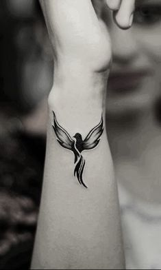 a woman's arm with a bird tattoo on the left side of her wrist