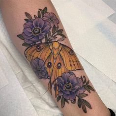 a yellow moth with purple flowers on it's leg