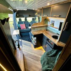 the interior of a camper van with wood flooring and blue couches in it