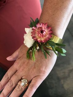 a close up of a person's hand wearing a ring and flower on her wrist