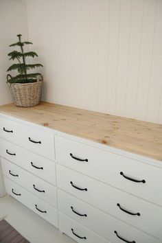 a white dresser with drawers and a potted plant sitting on it's top