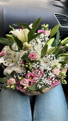 a bouquet of flowers sitting on the back seat of a car in someone's lap