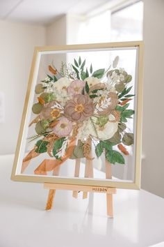 an easel with flowers on it sitting on a table