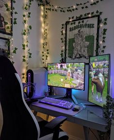 two computer monitors sitting on top of a desk in front of a wall with pictures