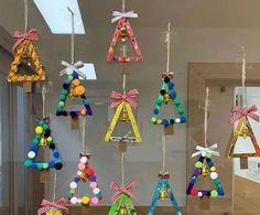 a group of colorful ornaments hanging from strings on a wall in front of a window