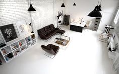 a living room filled with furniture and lots of white bricks on the wall behind it