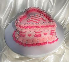 a heart shaped cake with pink frosting and pearls