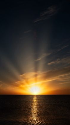 the sun is setting over the ocean with bright rays coming from behind it and reflecting in the water