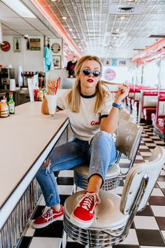 a woman sitting at a diner counter with her feet up on the bar stools