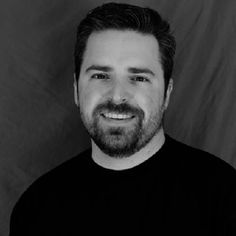 a black and white photo of a man with a goatee smiling at the camera