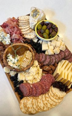 an assortment of cheeses, meats and crackers on a platter