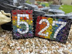 two pieces of colorful glass sitting on top of gravel