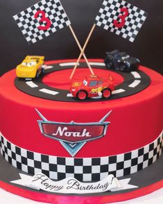 a birthday cake with cars on it and two flags in the shape of race cars