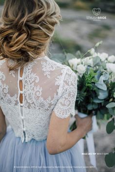 the back of a bride's dress holding her bouquet