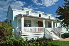 a white house with blue siding and green trees