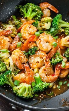 shrimp and broccoli stir fry in a wok with sesame seeds on the side