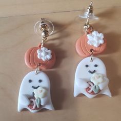 two ghost keychains with flowers on them are sitting on a table next to each other