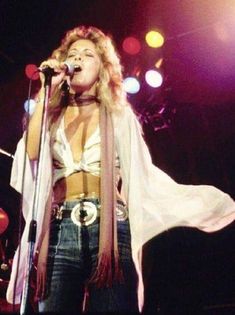 a woman standing in front of a microphone on stage