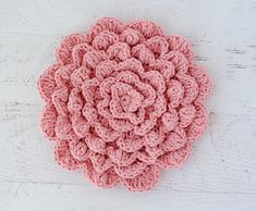 a pink crocheted flower sitting on top of a white table