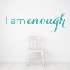 a white chair sitting in front of a wall that says i am enough