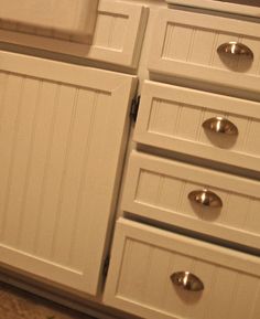 a kitchen with white cabinets and silver knobs