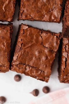 chocolate brownies cut into squares and placed on a white surface with chocolate chips around them