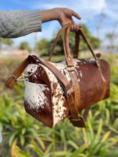 cowhide fur travel bag, turn heads on your trip with this unique weekender duffel. soft genuine fur & spacious interior. - Free shipping on all our cowhide weekender bags - Size: L=18" H=11" W=8.5" inches - Open with zipper closure for easy access - Adjustable and detachable sling with padded support for comfortable carrying - Inside zipper and plain compartment for organized storage - Backside zipper on the bag for additional convenience - Lower studs provided for added protection and stability Cowhide Purse, Weekender Bags, Leather Waist Bag, Real Leather Bags, Cowhide Bag, Organized Storage, Leather Apron, Leather Duffle Bag, Leather Duffle