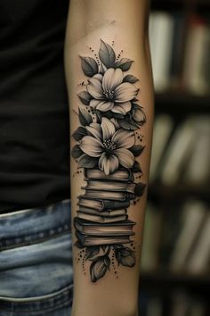 a woman's arm with a stack of books and flowers on it