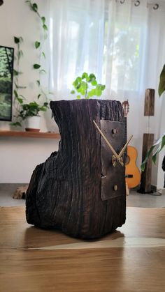 a clock made out of a piece of wood on top of a wooden table next to a window