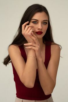 a woman in a red top is posing with her hands on her face and looking at the camera