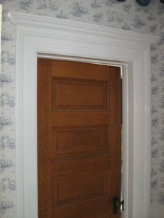 a wooden door in the corner of a room with wall paper on the walls behind it