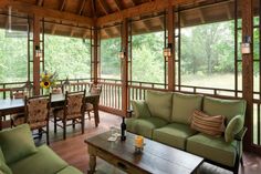 a living room filled with green furniture and lots of wooden windows covered in wood planks