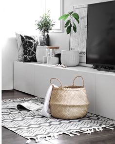 a flat screen tv sitting on top of a white shelf next to a potted plant