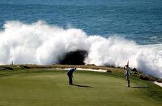 two people playing golf in front of a large wave crashing over the ocean on a golf course