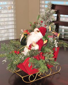 a santa clause sitting on top of a sleigh filled with christmas greenery