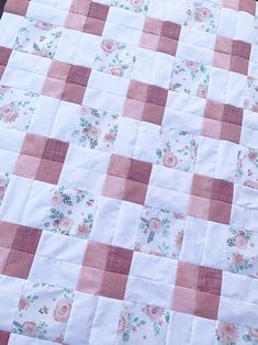 a pink and white quilt with flowers on it