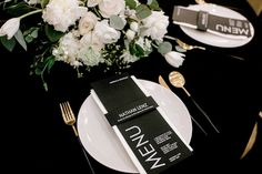 a table setting with white flowers and black napkins