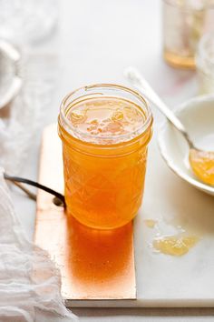 a glass jar filled with liquid sitting on top of a white plate next to a spoon