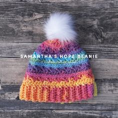 a multicolored knitted hat with a white pom - pom on top