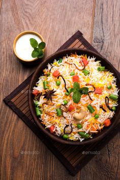 a bowl filled with rice and vegetables on top of a wooden table