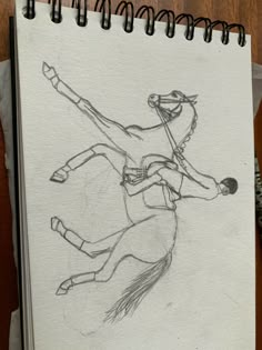 a drawing of a man riding a horse on top of a wooden table next to a notebook